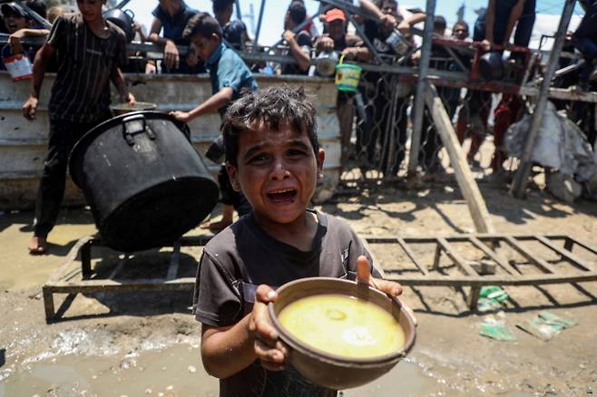 24일(현지시간) 가자지구 가자시티 자선 급식소에서 한 팔레스타인 어린이가 구호 음식을 받아 들고 있다. /신화=뉴시스