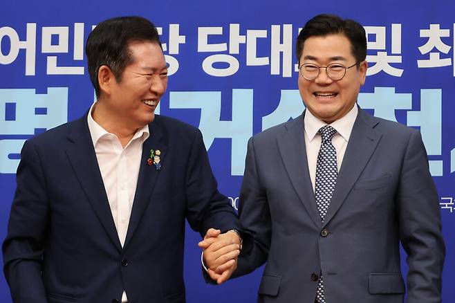 더불어민주당 정청래·박찬대(오른쪽) 당대표 후보가 15일 서울 여의도 국회에서 열린 공명선거 실천 서약식에서 서약문에 서명한 뒤 손을 잡고서 기념촬영 하고 있다. ⓒ연합뉴스