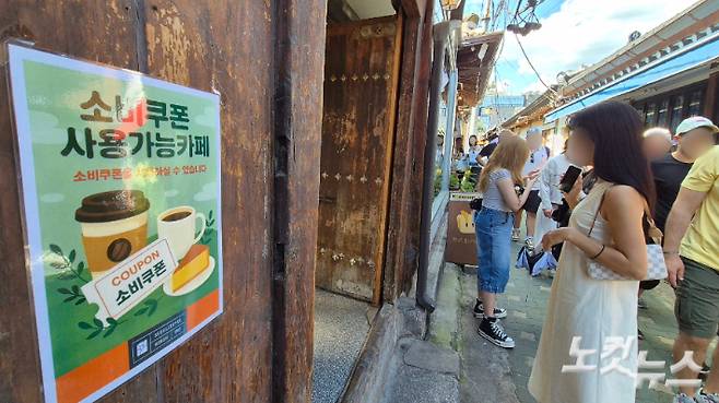 27일 오후 서울 종로구 익선동 골목이 사람들로 붐비는 가운데 한 카페 입구에 민생회복 소비쿠폰 사용이 가능하다는 홍보물이 붙어 있다. 송선교 기자