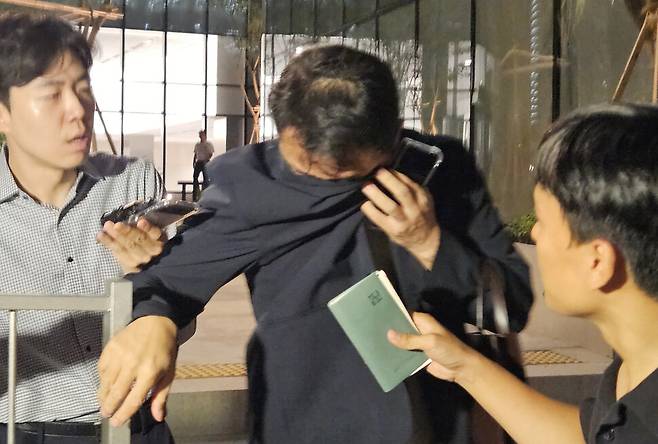 김건희 여사 오빠인 김진우씨가 28일 밤 김 여사 관련 의혹들을 수사하는 민중기 특별검사팀 사무실이 위치한 서울 종로구 케이티(KT)광화문빌딩웨스트(West)에서 조사를 마친 뒤 얼굴을 가린 채 특검 사무실을 나서고 있다. 연합뉴스