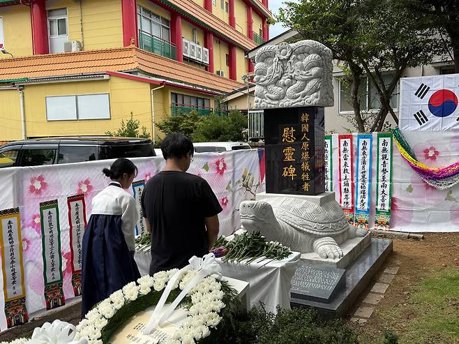 8일 일본 나가사키 한국인 원폭 희생자 위령비 앞에서 열린 80주년 추모제에서 한복 차림의 참석자가 헌화 후 희생자 넋을 기리고 있다.