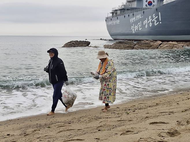 김복강씨(우측)와 막내딸이 지난 9일 새벽 5시쯤부터 영덕 장사해수욕장 모래위에 파도에 밀려온 해안가 쓰레기를 남들 몰래 주워 봉투에 넣은 후 걸어가고 있다.(영남일보 DB)