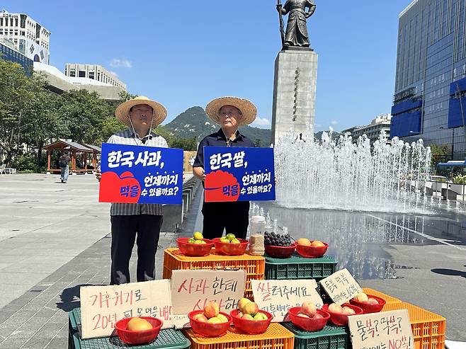 Apple farmer Ma Yong-un (left) and rice farmer Hwang Seong-yeol hold posters reading “Until when will we be able to eat Korean apples / rice?” at a press conference in Gwanghwamun Square, central Seoul, on Tuesday. The event, hosted by climate advocacy group Solutions for Our Climate, announced a lawsuit against Korea Electric Power Corporation and five of its subsidiaries over climate-related damages. (Lee Jung-joo/The Korea Herald)