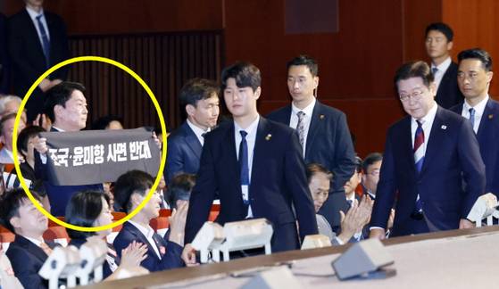 안철수 국민의힘 의원이 15일 서울 세종문화회관에서 열린 80주년 광복절 경축식에서 이재명 대통령이 경축사를 마치고 자리를 향할 때 '조국·윤미향 사면 반대'라는 문구가 적힌 펼침막을 들어보이고 있다. 〈사진=대통령실통신사진기자단/연합뉴스〉