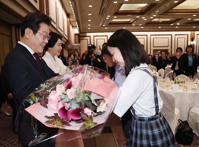한일 정상회담을 위해 일본을 방문 중인 이재명 대통령과 김혜경 여사가 23일(현지 시간) 일본 도쿄의 한 호텔에서 열린 재일동포 오찬 간담회에서 화동에게 꽃다발을 받고 있다. 도쿄=뉴시스