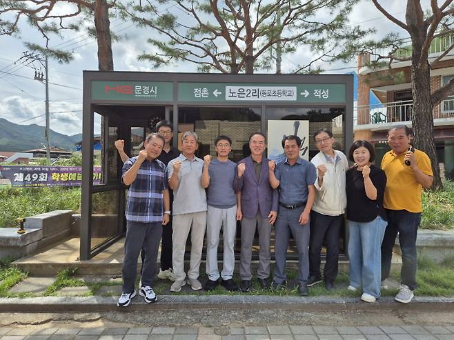 문경시 동로면 버스 승강장에 버스 시간표, 시계, 거울을 설치한 두클럽 회원들과 송영복 동로면장(오른쪽 네 번째). /문경시 제공