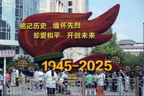 중국의 항일전쟁 및 세계 반파시스트 전쟁(제2차 세계대전) 승리 80주년(전승절) 기념 열병식을 사흘 앞둔 31일 중국 베이징 천안문 인근 거리에 설치된 꽃 조형물 앞에서 행인들이 기념 사진을 찍고 있다. 뉴스1