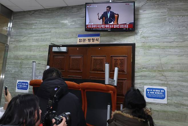 2024년 12월4일 새벽 국회 본회의장 앞에서 계엄군을 막아선 국회 관계자들이 생중계 화면을 통해 비상계엄 해제 요구 결의안 가결 모습을 지켜보고 있다. ⓒ연합뉴스