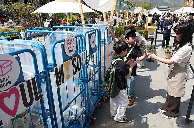 서울 종로구 광화문광장에서 열린 '2024 지구의 날' 기념행사에서 한 어린이가 분리수거를 한 후 화분을 받고 있다. 2024.4.13 (ⓒ뉴스1, 무단 전재-재배포 금지)