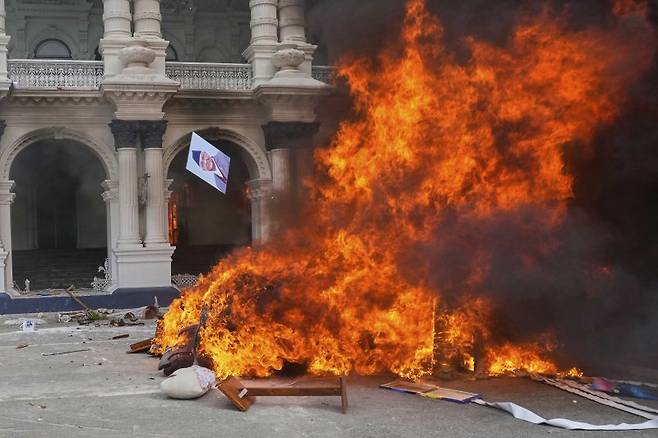 네팔 카트만두에서 SNS 금지 및 부패 반대 시위 중 한 시위자가 네팔 총리 카드가 프라사드 올리의 사진을 불 속에 던지고 있다. /사진=연합 지면외신화상(AP)