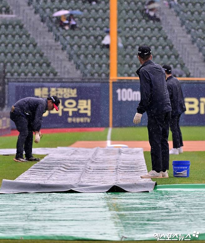 12일 오후 서울 송파구 잠실야구장에서 열리는 '2025 신한 SOL Bank KBO리그' 두산 베어스와 LG 트윈스의 경기, 비바람이 부는 가운데 야구장 관계자들이 방수포를 설치하고 있다. 엑스포츠뉴스 DB