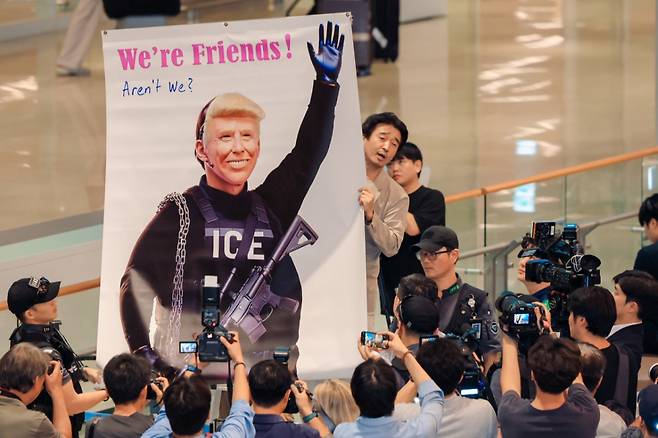 (인천공항=뉴스1) 박지혜 기자 = 미국 이민당국에 의해 체포·구금됐다 풀려난 한국인 316명이 탑승한 전세기가 인천국제공항 2터미널에 도착한 12일 이제석 이제석광고연구소 대표가 공항 입국장에서 트럼프 미국 대통령의 모습이 담긴 플래카드 퍼포먼스를 벌이고 있다. (공동취재)2025.9.12/뉴스1 Copyright (C) 뉴스1. All rights reserved. 무단 전재 및 재배포, AI학습 이용 금지. /사진=(인천공항=뉴스1) 박지혜 기자