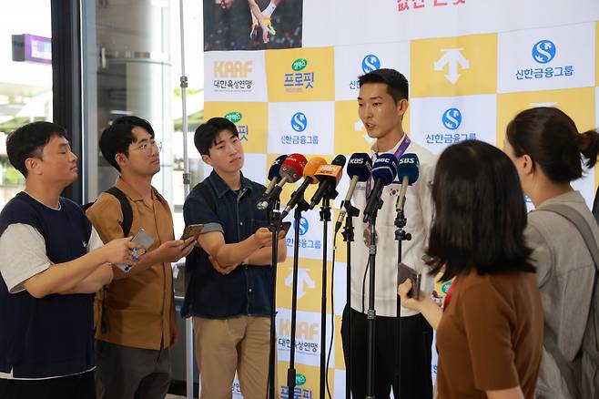 ‘스마일 점퍼’ 우상혁(왼쪽 4번째)이 18일 김포공항에서 열린 귀국 기자회견에서 2025세계육상선수권 남자 높이뛰기에서 은메달을 수확한 소감을 설명하고 있다. 그는 지난달 10일 유럽전지훈련 도중 종아리와 발목을 다쳤지만 이를 딛고 한국육상 역대 최고 성적과 타이인 은메달을 따냈다. 사진제공│대한육상연맹