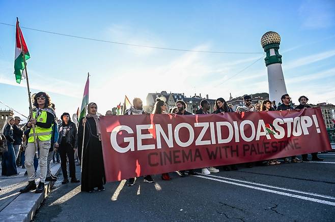 스페인 북부 바스크 지역 산세바스티안에서 열린 제73회 산세바스티안 국제영화제 기간, 영화계 관계자들이 참여한 친팔레스타인 시위 참가자들이 “학살을 멈춰라, 팔레스타인과 함께하는 영화”라는 구호를 내걸고 행진하고 있다. AFP
