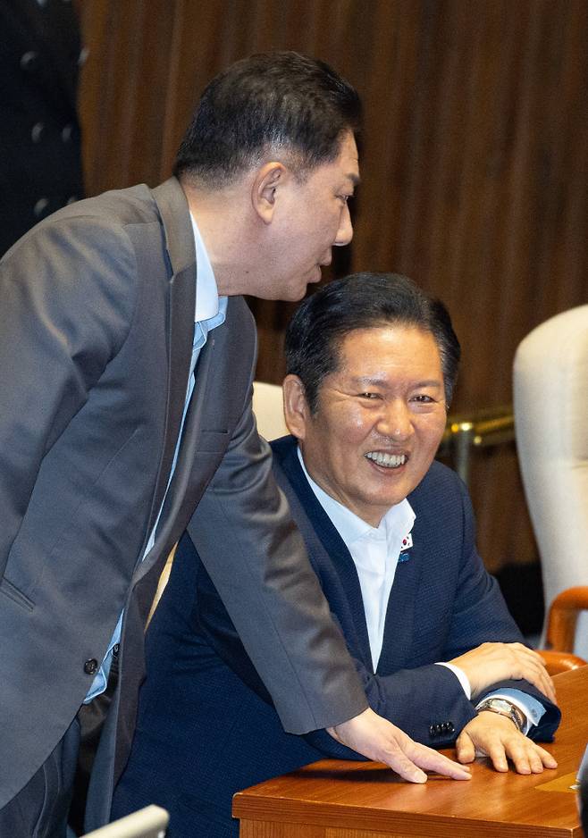 더불어민주당 정청래 대표(오른쪽)가 27일 서울 여의도 국회에서 열린 본회의에서 김병기 원내대표와 대화하며 미소를 짓고 있다. 이날 민주당 등 범여권은 방송미디어통신위원회 설치법에 대해 국민의힘이 신청한 필리버스터(무제한 토론)를 강제 종결시키고 법안을 통과시켰다. 뉴스1