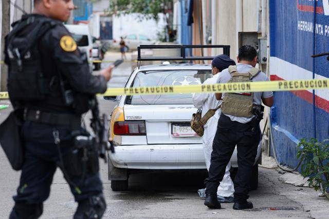 법의학 전문가들이 7월 31일 멕시코 아카풀코에서 택시 안에서 여성을 포함한 두 구의 시신이 발견된 현장에서 수사를 하고 있다. 아카풀코=EPA 연합뉴스