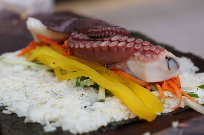 문어, 당근, 오이, 적양배추, 단무지, 계란지단을 넣고 문어 김밥을 만들고 있다.