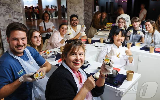 29일(현지시간) 스페인 마드리드 아르테스 예술센터에서 열린 ‘2025 스페인 K-박람회’에서 한국농수산식품유통공사 ‘K-FOOD’ 부스 한식 쿠킹클래스 김밥 아틀리에에 참가한 현지인들이 김예림 셰프와 함께 만든 김밥을 들어 보이고 있다. (사진가 우채연 제공, 재판매 및 DB금지) 2025.9.30/뉴스1 ⓒ News1 이준성 기자