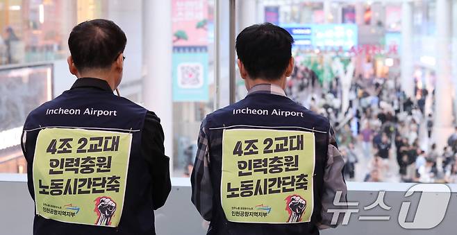 무기한 파업에 들어간 공항 노동자들이 1일 인천국제공항 1터미널에서 출국하는 여행객들을 바라보고 있다. 2025.10.1/뉴스1 ⓒ News1 박지혜 기자