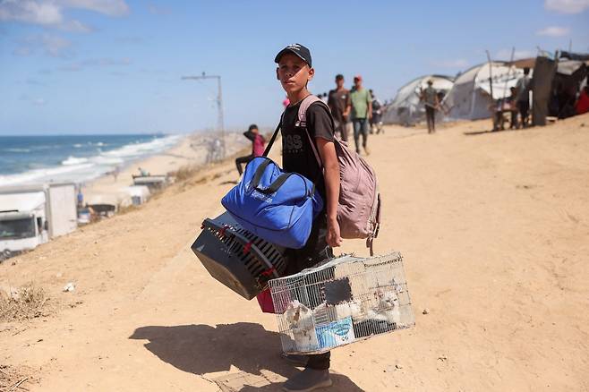 고양이들 데리고…어디로 가야 하나 1일(현지시간) 가자지구 북쪽 알라시드 도로를 폐쇄한다는 이스라엘의 발표로 팔레스타인인들이 남쪽으로 피란하는 가운데 한 청년이 고양이와 소지품을 든 채 걸어가고 있다. AFP연합뉴스