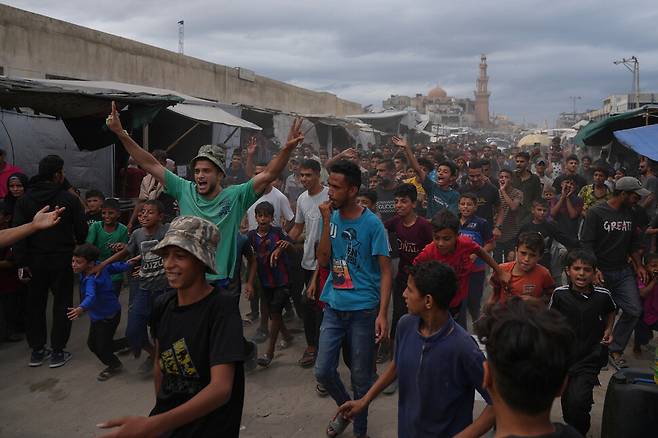 팔레스타인 주민들이 9일(현지시각) 가자지구 남부 칸유니스 거리에서 이스라엘과 하마스가 트럼프 중재안의 1단계 협정에 합의했다는 소식이 전해지자 기뻐하고 있다. 가지지구/AP 연합뉴스