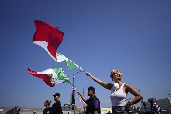 10일(현지시간) 미 캘리포니아주 로스앤젤레스에서 멕시코 국기를 든 시위대가 이민세관단속국(ICE)의 불법 이민자 단속을 규탄하고 있다.AP뉴시스