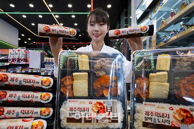 모델이 세븐일레븐 제주흑돼지 간편식 2종을 소개하고 있다. (사진=세븐일레븐)