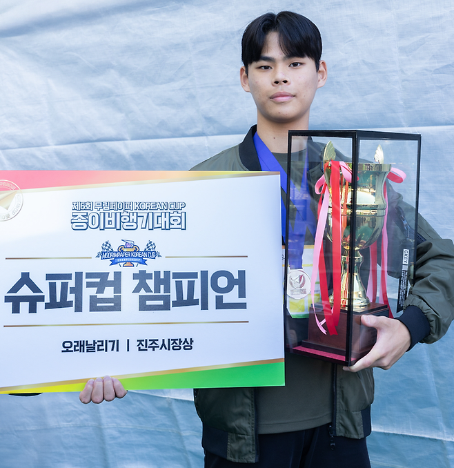 종이비행기대회 오래날리기 1위 오시언 군이 우승컵을 들고 있다. /무림
