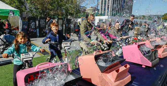27일 서울 종로구 광화문광장에서 제3회 지구하다 페스티벌이 열린 가운데 외국인 관광객 가족들이 자가발전 자전거 체험을 하고 있다.