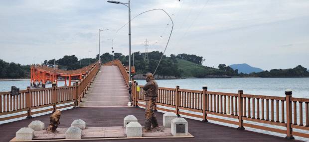 여자도 해안 데크길에서 연도교로 연결된 송여자도 전경. 여자도는 대여자도, 송여자도는 소여자도로도 불린다. 연도교 입구에 설치된 낚싯꾼 조각상.