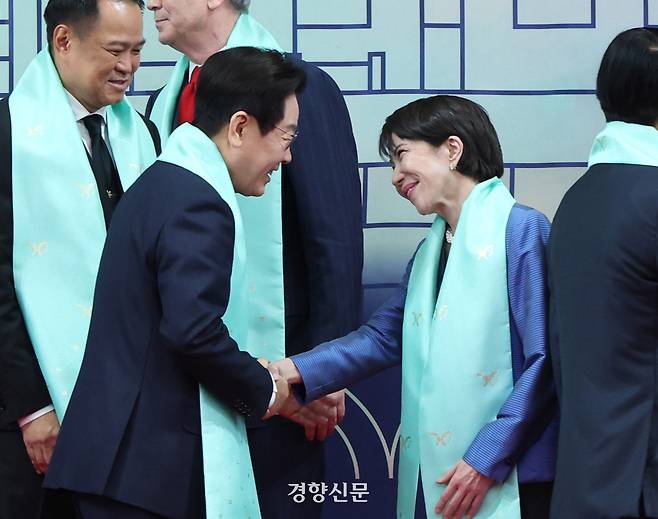 이재명 대통령이 1일 경북 경주 화백컨벤션센터에서 아시아태평양경제협력체(APEC) 정상회의에 참석한 각국 정상들과 전통 한복 목도리를 하고 단체 기념촬영을 마친 후 다카이치 사나에 일본 총리와 악수하고 있다. 목도리에는 APEC 정상회의 엠블럼과 한글 자음 모음이 금박으로 새겨져 있다. 경주/김창길 기자