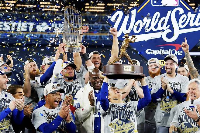 야마모토 요시노부(왼쪽에서 세 번째)가 2025 미국프로야구 메이저리그 월드시리즈 7차전 승리 후 열린 시상식에서 최우수선수(MVP)로 선정된 뒤 동료들의 축하 속에 트로피를 머리 위로 들어올리고 있다. 데이브 로버츠 다저스 감독과 매직 존슨 구단주도 환한 미소로 축하의 박수를 보내고 있다. 토론토=AP 뉴시스