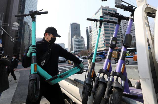 2022년 3월 서울 중구 서울광장 인근 횡단보도에서 킥보드 업체 관계자가 킥보드 수거 장면을 연출하고 있다. 뉴시스