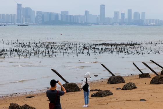 지난 10월 멀리 중국 푸젠성 샤먼시 해변이 보이는 대만 진먼다오에서 관광객이 중국군의 상륙을 막는 구조물 주변에서 사진을 촬영하고 있다. 로이터=연합뉴스