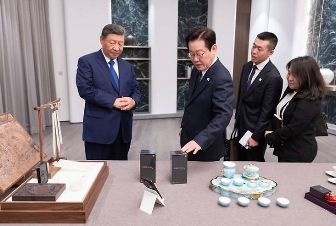 이재명 대통령과 시진핑 중국 국가주석이 1일 경주에서 정상회담에 앞서 이 대통령은 시 주석에게 최고급 바둑판 세트와 나전칠기 쟁반을, 시 주석은 이 대통령에게 샤오미 스마트폰과 문방사우 세트를 선물했다. 주고 받은 선물을 함께 살펴보는 두 정상. 대통령실 제공