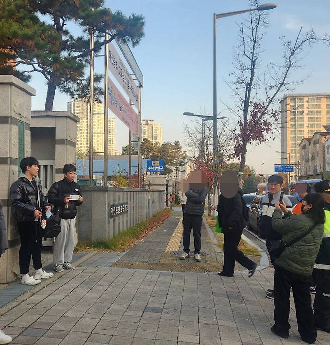 수능일인 13일 대전 서구 도안고 수험장 앞에서 함은균 씨가 시험을 치르기 전 수험표를 들고 의지를 다지는 아들의 모습을 촬영하는 모습 (사진=정바름 기자)