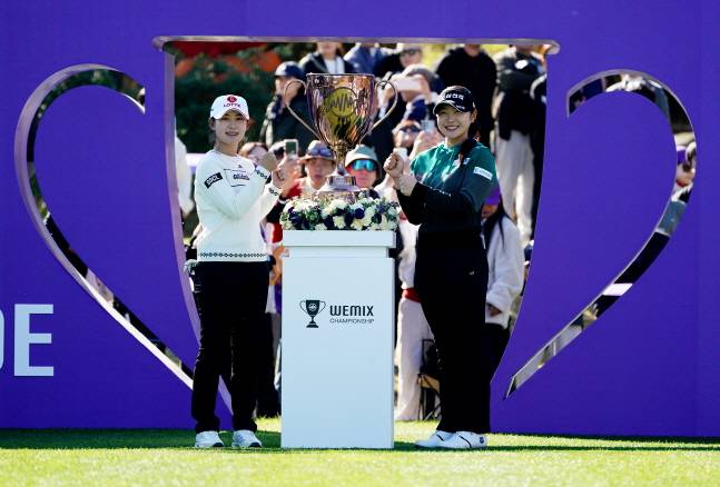 황유민(왼쪽)이 1번 홀 티샷을 앞두고 유현조와 트로피를 사이에 두고 기념 촬영을 하고 있다. /사진=위메이드 제공