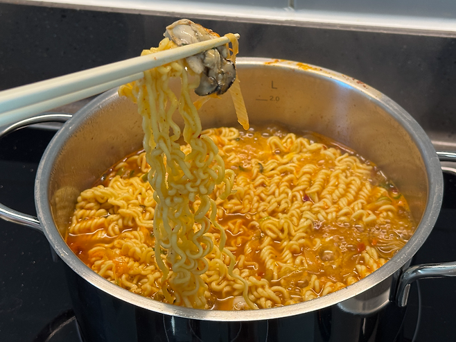 감칠맛 가득한 굴과 라면 면발을 함께 집어 올리는 모습