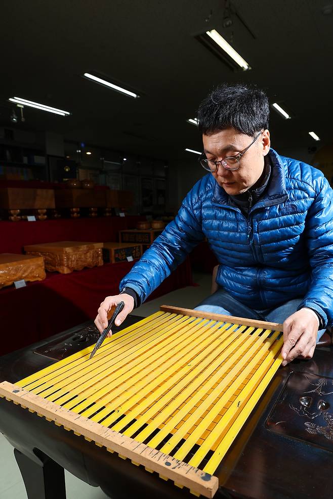 신 본부장이 특수 자를 사용해 먹줄을 긋고 있다.