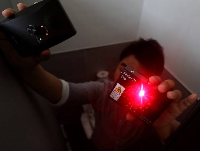 한국의 한 교육 당국자가 초소형 카메라 탐지장비를 이용해 교내 화장실에서 몰래카메라 설치 여부를 확인하고 있다.(자료사진/뉴스1)