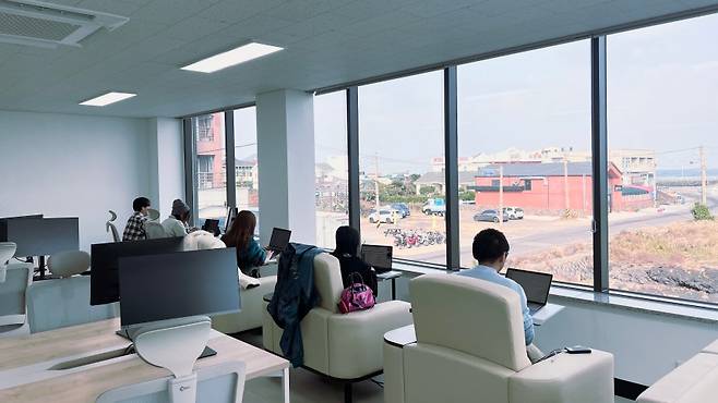 김녕 해안 앞 워케이션 데스크에서 일본 팸투어 참가자들이 바다를 두고 업무를 이어가고 있다. (제주관광공사 제공)