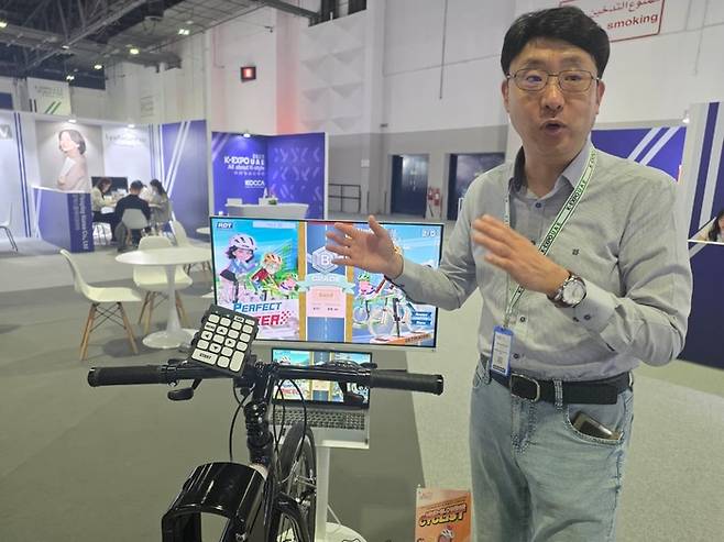 “중동은 날씨가 덥다보니 특히 이렇게 실내에서 운동할 수 있는 자전거에 관심이 많은 것 같아요.” 리얼디자인테크의 이중식 대표가 실내 자전거와 모니터, 그리고 AI를 결합한 솔루션을 설명하고 있다