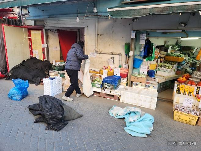 4일 오전 서울 마포구 망원시장의 한 청과물 가게 사장이 장사 준비를 하고 있다. 한파를 피해 매대 상품에 이불을 덮고 있다. 이영기 기자.