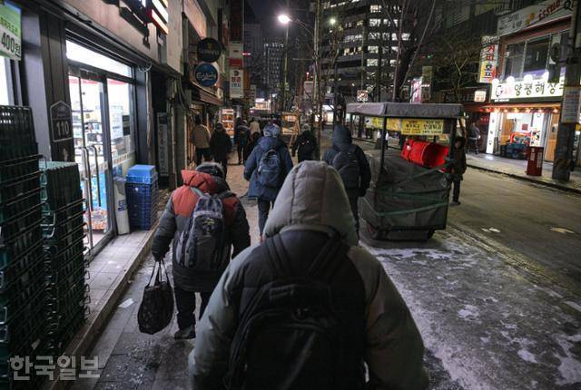 13일 이른 아침 서울 종로구 탑골공원 원각사 무료급식소에서 점심식사용 번호표를 수령한 노인들이 송해길에서 줄지어 걸어가고 있다. 이 노인들은 대부분 종로3가역에서 1호선을 타고 서울역으로 이동해 '아침애만나' 무료급식소에서 아침 식사를 먹거나, 근처의 '전국천사무료급식소'로 이동해 대기한다. 최주연 기자