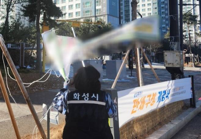 화성시 관계자가 불법현수막을 단속하고 있다.<화성시 제공>