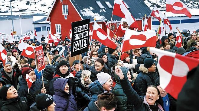 지난 17일 덴마크 자치령 그린란드 주민들이 그린란드 국기와 ‘그린란드는 판매용이 아니다’라는 구호가 적힌 팻말을 들고 수도 누크에 있는 미국 영사관 앞에 모여 항의 집회를 열고 있다. 최근 도널드 트럼프 미국 행정부가 그린란드를 미국으로 편입하겠다는 의지를 거듭 드러내자 이에 반발한 그린란드 주민들의 집회가 잇따르고 있다. /게티이미지코리아