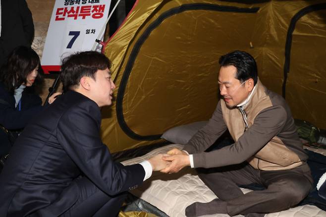 이준석 개혁신당 대표가 21일 서울 여의도 국회 로텐더홀에서 단식투쟁 7일차를 맞은 장동혁 국민의힘 대표를 찾아 대화를 하고 손을 잡고 있다. 윤창원 기자