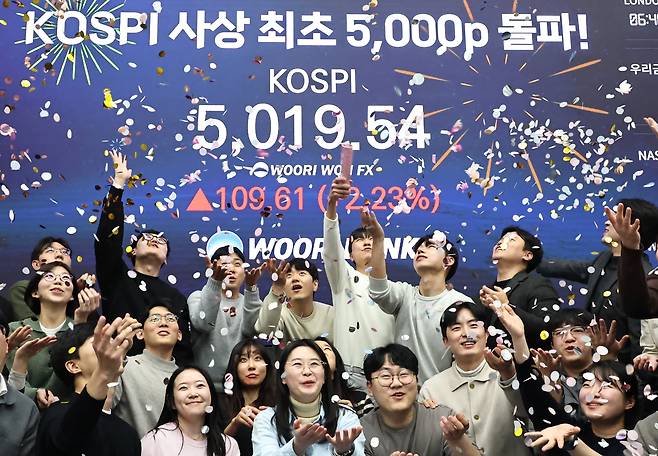 코스피 지수가 장중 사상 처음으로 5,019.54를 기록한 22일 서울 중구 우리은행 본점 딜링룸에서 딜러들이 코스피 지수 5,000선 돌파를 축하하고 있다./연합뉴스