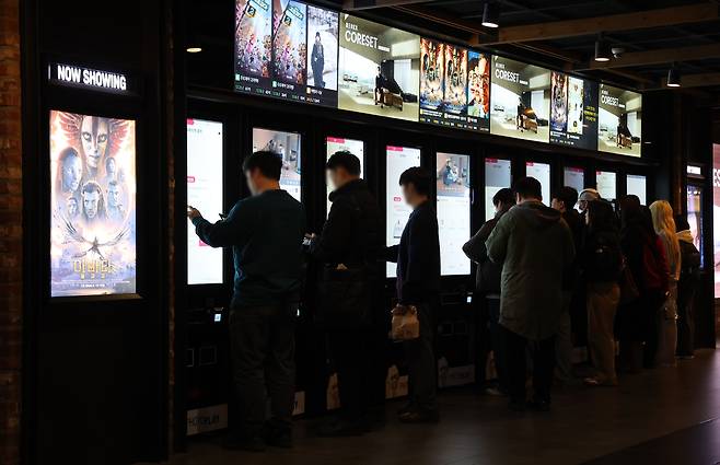 지난해 12월 28일 서울 시내 한 영화관을 찾은 시민들이 영화 예매를 하고 있다.