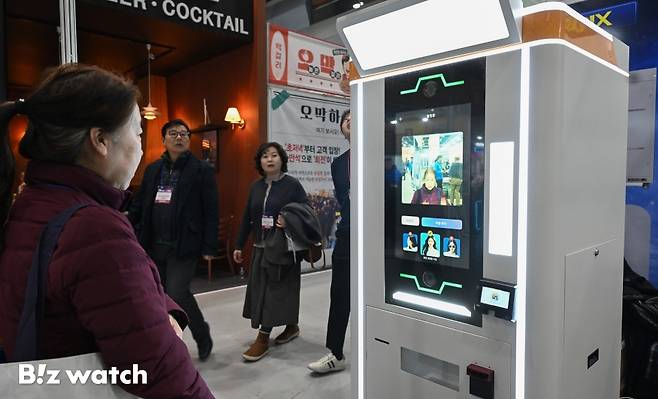 15일 서울 강남구 코엑스에서 열린 '프랜차이즈 창업 박람회 2026'을 찾은 관람객들이 AI기술을 활용한 기념주화 제작 부스를 둘러보고 있다./사진=이명근 기자 qwe123@